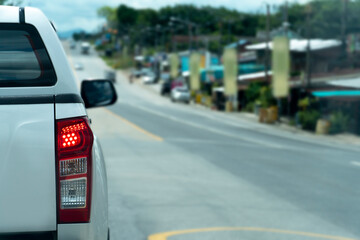 Transportation of pick up car white color on the road. Open brake light. Heading to travel or work in rural areas. 