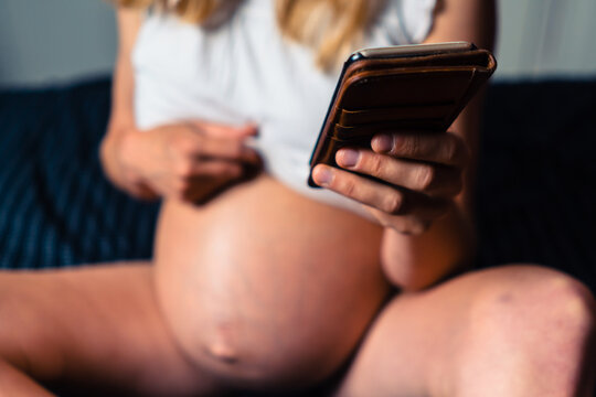 Pregnant woman using smartphone in bed