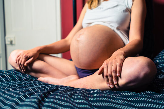 Young pregnant woman sitting in calm pose on a bed
