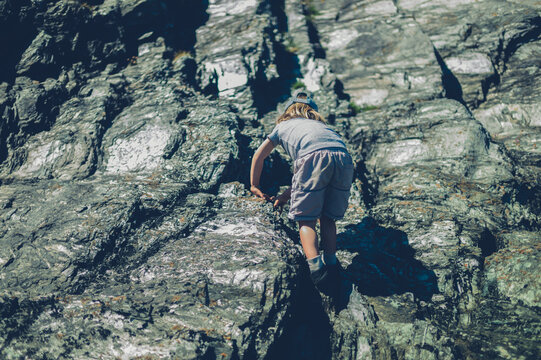Preschooler boy climbing rocks in spring