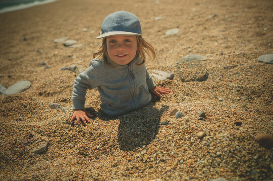 Preschooler boy playing in the pebbles on the beach