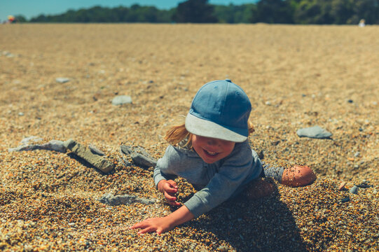 Preschooler boy playing in the pebbles on the beach