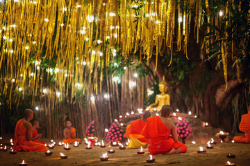 Monks sitting meditate with many candle in Thai temple at night