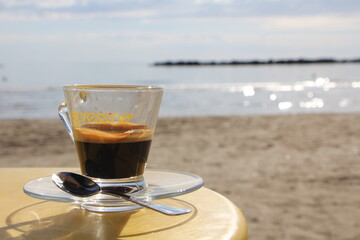 Coffee cup on the beach, with sand, water. Holiday and relax time