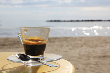 Coffee cup on the beach, with sand, water. Holiday and relax time
