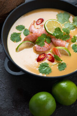 Thai-style soup with prawns, pumpkin, coconut milk, red chili, lime and coriander, vertical shot, closeup