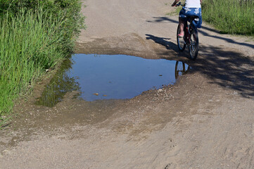 Dirt road with puddles in summer with grass side