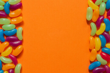 Assorted Jelly Beans border with copyspace on orange background.