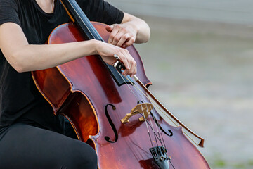 Woman playing a double bass during a performance or music recital. closeup hands, the instrument and bow.