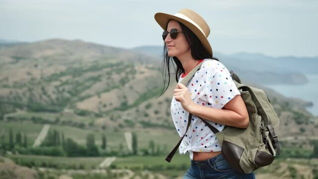 Smiling young travel woman walking on top of mountain over sea. Medium shot on RED camera