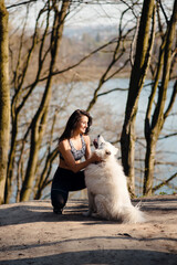 Beautiful sporty girl in hugging white purebred dog outdoors