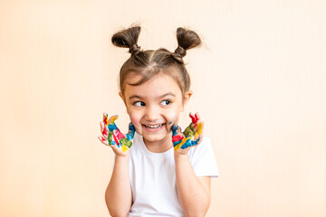 Happy little girl with painted hands. the child joyfully shows his palms painted with paints. painted children's palms
