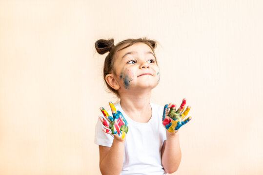 Happy little girl with painted hands. the child joyfully shows his palms painted with paints. painted children's palms