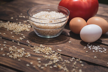 Cuban rice ingredients: tomato, rice and eggs on a wooden background