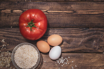 Cuban rice ingredients: tomato, rice and eggs on a wooden background