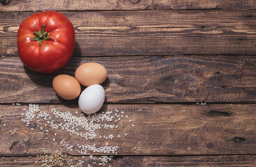Cuban rice ingredients: tomato, rice and eggs on a wooden background