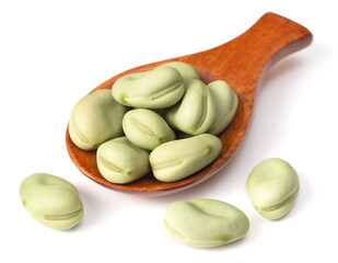 uncooked dried green faba beans in the wooden spoon, isolated on white background
