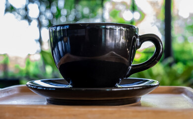 Wood table with cup of latte coffee in morning garden, side view.