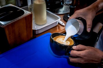 Barista pouring milk in coffee cup for make cappuccino art.