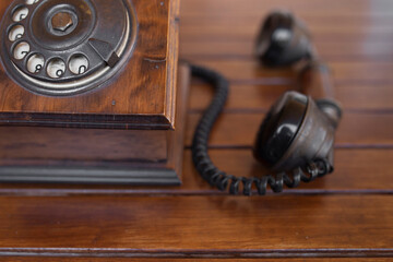 overhead view vintage wooden telephone in the foreground off the hook on a wooden table