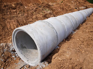 Closeup - a round concrete drainage pipe on the ground. On the ground background in the...