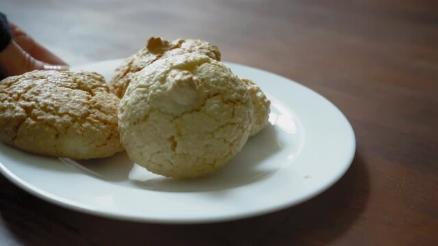 Hand put a white plate with cookies on the dark wooden table. Biscuits for your coffee. Prores 422. 