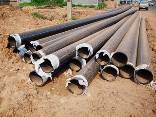 Black HDPE plumbing on the ground beside the road. Round plastic pipes in the construction of water...