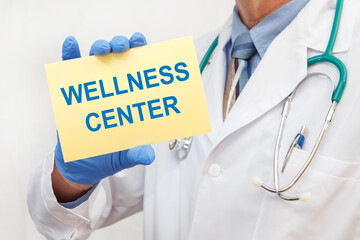 Close-up of a male doctor holding a sign with the text WELLNESS CENTER