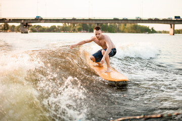 young sports man wakesurfer balancing on the wave