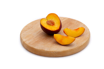 peach or nectarine with cut pieces on a wooden plate