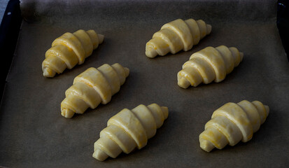 A parchment with fresh raw butter croissants. Homemade bakery. Preparation to bake.