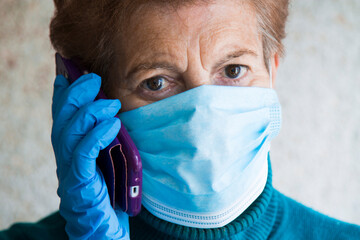 senior woman using mobile phone with mask and disposable medical gloves. Safety measures during the coronavirus outbreak