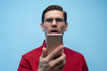 Portrait of a shocked young man with smartphone