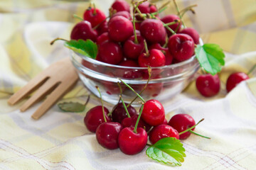 glass bowl with red cherries on yellow tablecloth