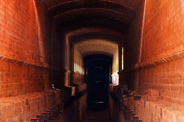 Old ruined brick vaulted tunnel. Dark passage. Underground communication