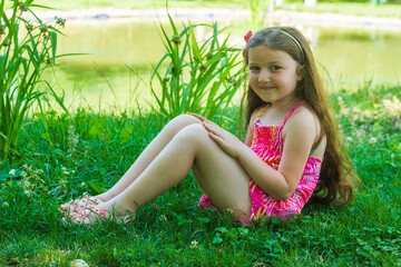 Naklejka na ściany i meble pretty little girl is sitting on the grass