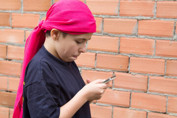 girl sick with cancer and with a headscarf using the mobile phone