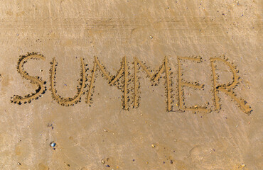 The word summer written by a stick on the sand of a beach