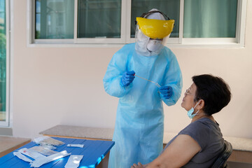 The doctors in the PPE protective suit performed a nasal congestion swab covid from a person to...
