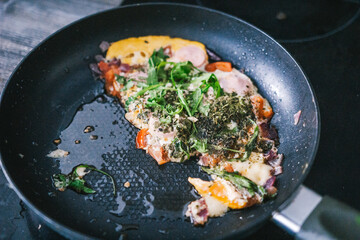 Ufa, Russia march 28, 2020 ready fried eggs in a pan on a plate with vegetables, herbs, sausage