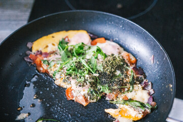 Ufa, Russia march 28, 2020 ready fried eggs in a pan on a plate with vegetables, herbs, sausage