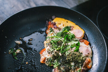 Ufa, Russia march 28, 2020 ready fried eggs in a pan on a plate with vegetables, herbs, sausage