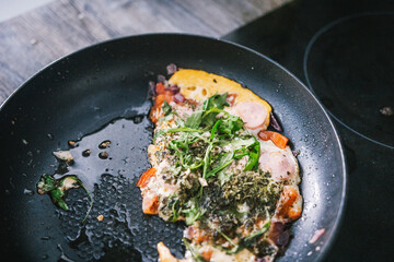 Ufa, Russia march 28, 2020 ready fried eggs in a pan on a plate with vegetables, herbs, sausage