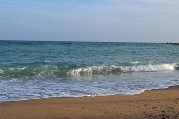 small waves of the Mediterranean Sea roll ashore from pebbles and stones in the afternoon