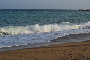 small waves of the Mediterranean Sea roll ashore from pebbles and stones in the afternoon