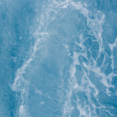 Pale blue sea surface with waves at high tide and surf, abstract background