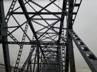 Metal construction of the railway bridge with the rising middle part for the passage of ships. View from below from the car window. Architecture, design elements