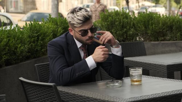 Confident Man In Suit Lighting Cigar, Relaxing At Restaurant Terrace, Elite Mens Club Outdoor