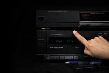 Fototapeta na wymiar Woman hand inserting compact cassette tape in old player audio are retro technology