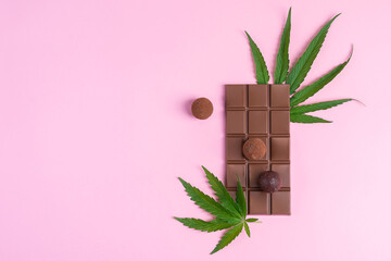 Dark chocolate and cannabis cannabis leaf on pink background. Horizontal frame copy space top view.
